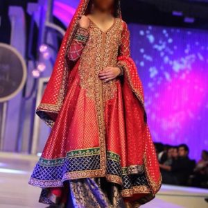 Beautiful wedding sharara dress in carmine pink color. Embellished v-neck full sleeves asymmetrical hem long bridal shirt with bridal sharara and bridal dupatta